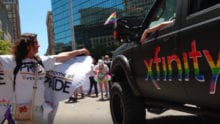 Participants in a Pride parade walk down a street.